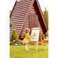 Child painting on an outdoor easel in front of a wooden playhouse