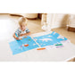 Child coloring on a large blue mat with markers in a home setting