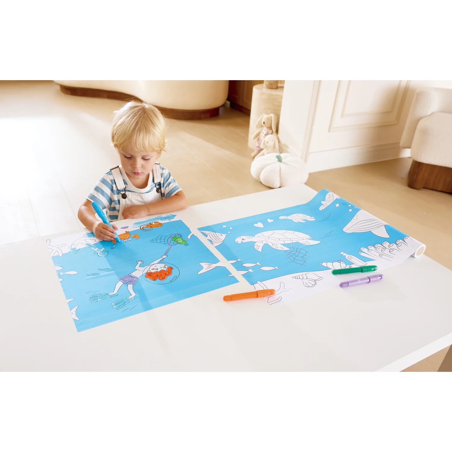 Child coloring on a large blue mat with markers in a home setting