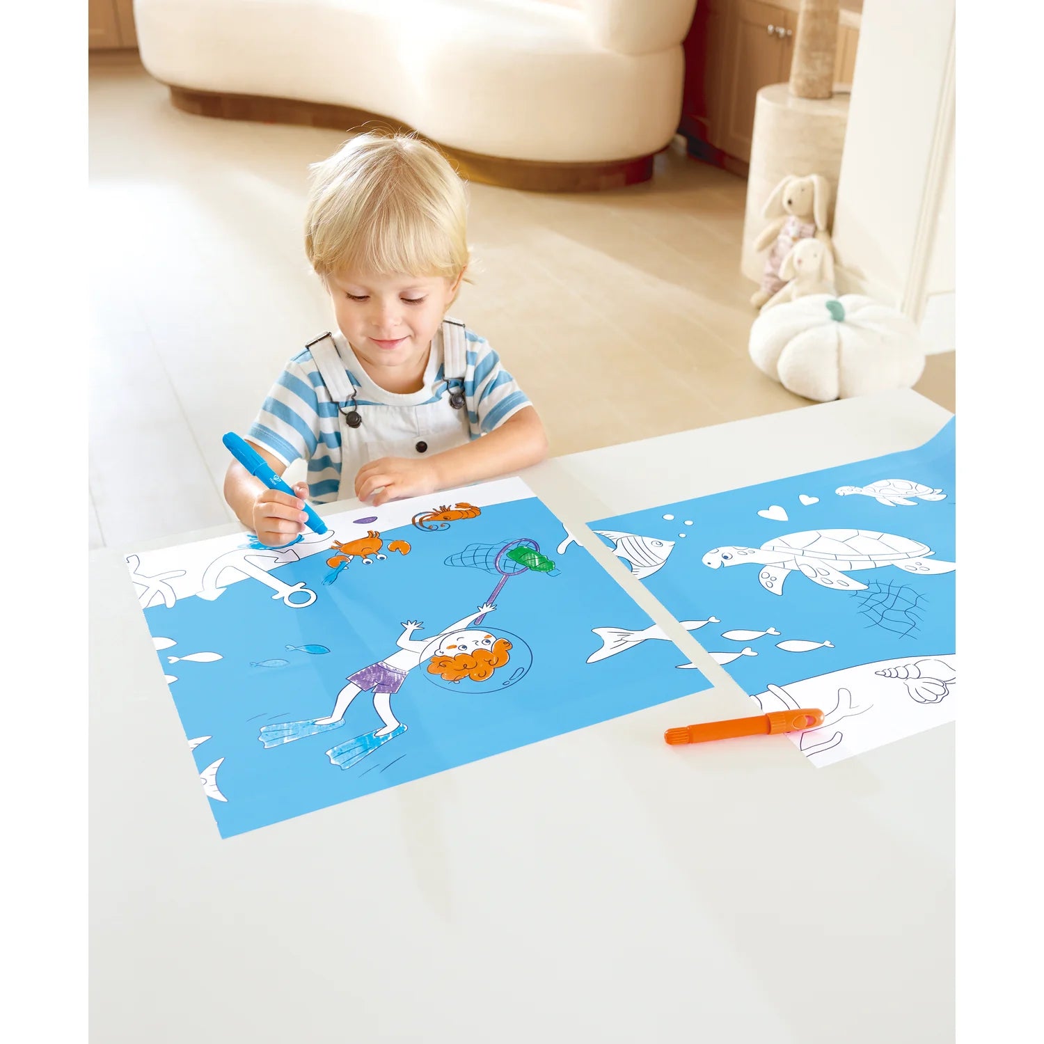 Child coloring on a mat with ocean-themed designs in a living room setting.