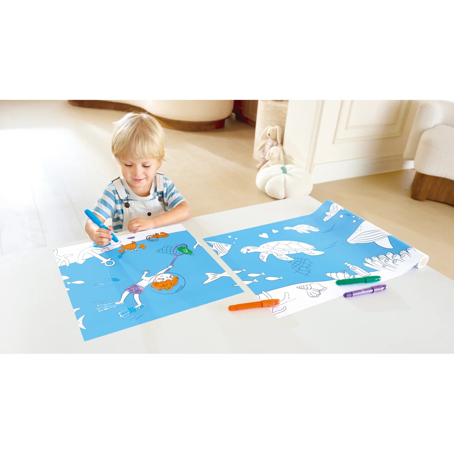 Child drawing on a blue mat with markers in a home setting