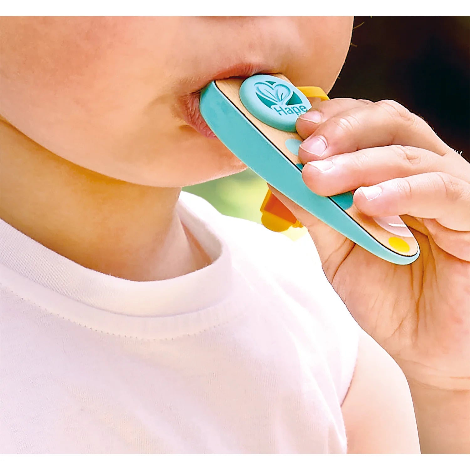 Child using a teal and green toothbrush with a visible brand logo.