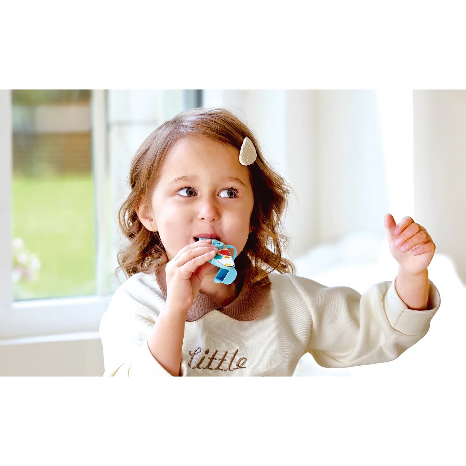 Child brushing teeth with a colorful toothbrush indoors