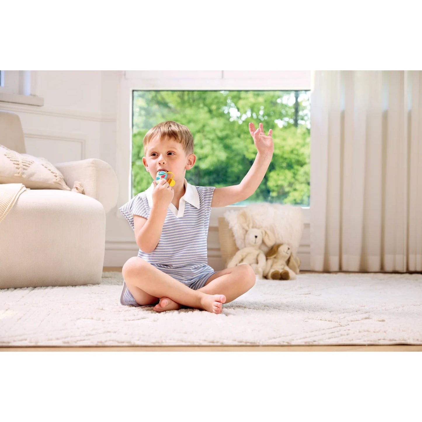 Child sitting on a rug in a bright room with a window in the background