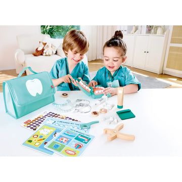 Two children playing with a toy dental set on a table.