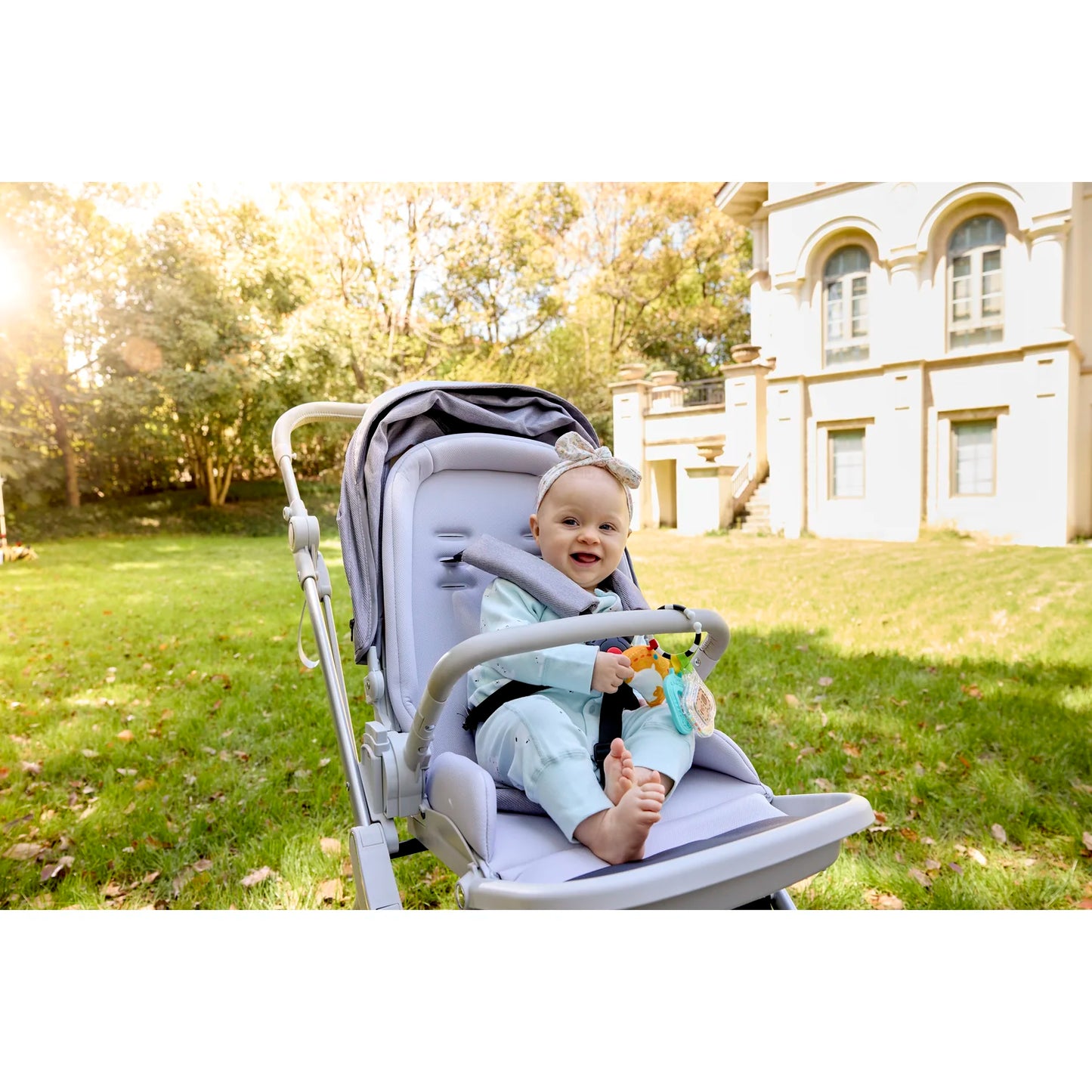 Child in a stroller with a teddy bear in a park setting
