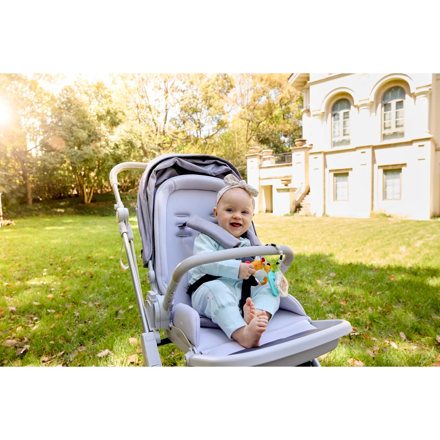 Child in a stroller with a teddy bear in a park setting