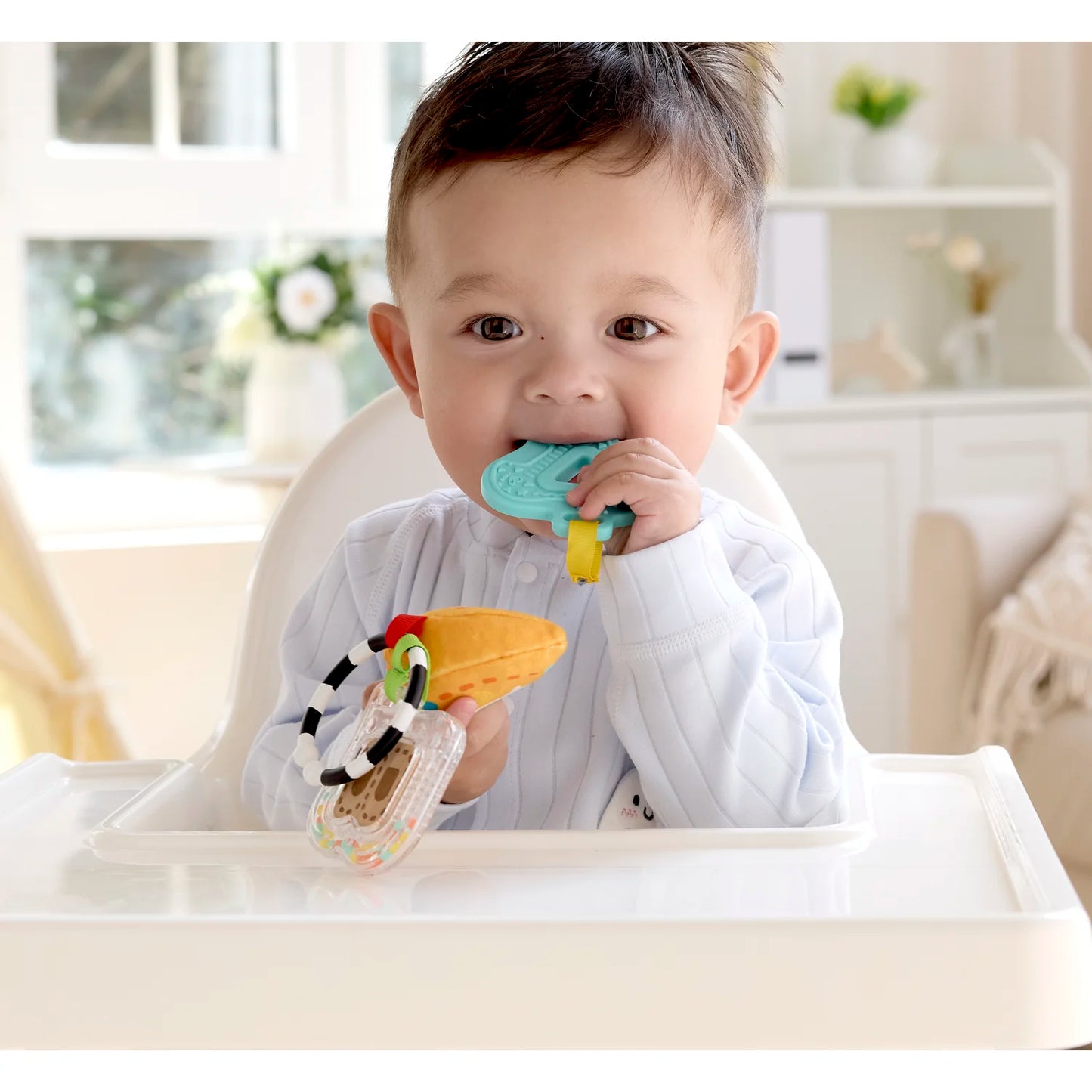 Baby sitting in a high chair with colorful teething toys
