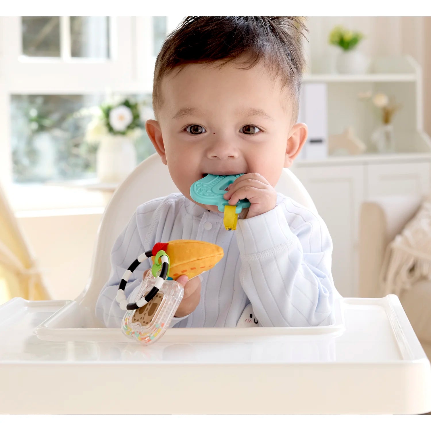 Baby sitting in a high chair with colorful teething toys