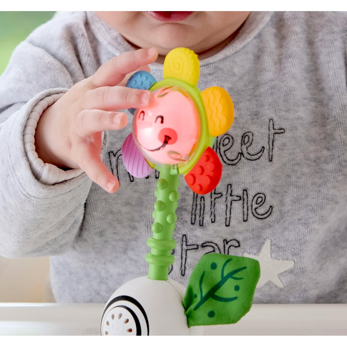 Child holding a colorful flower-shaped toy with a smiling face.