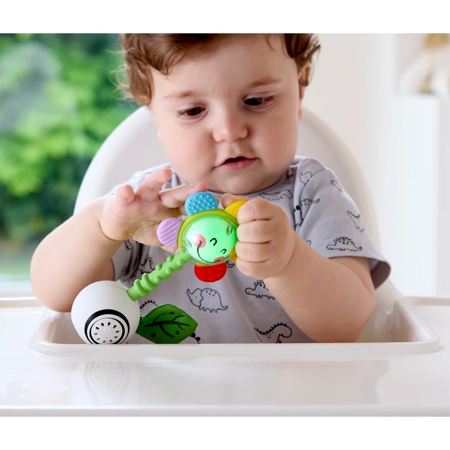 Child playing with a colorful baby toy in a high chair.