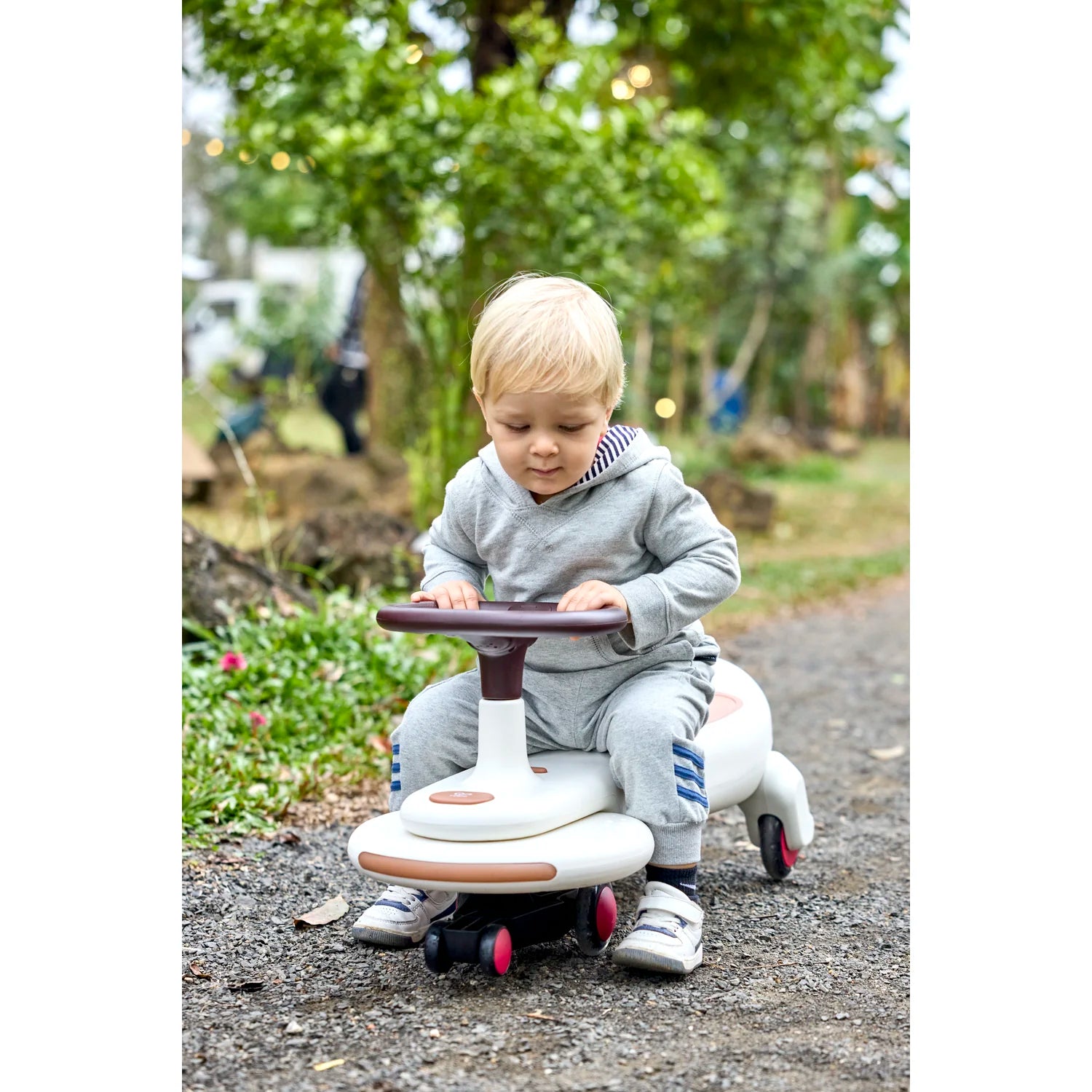 Child playing with a toy car on a path in a park
