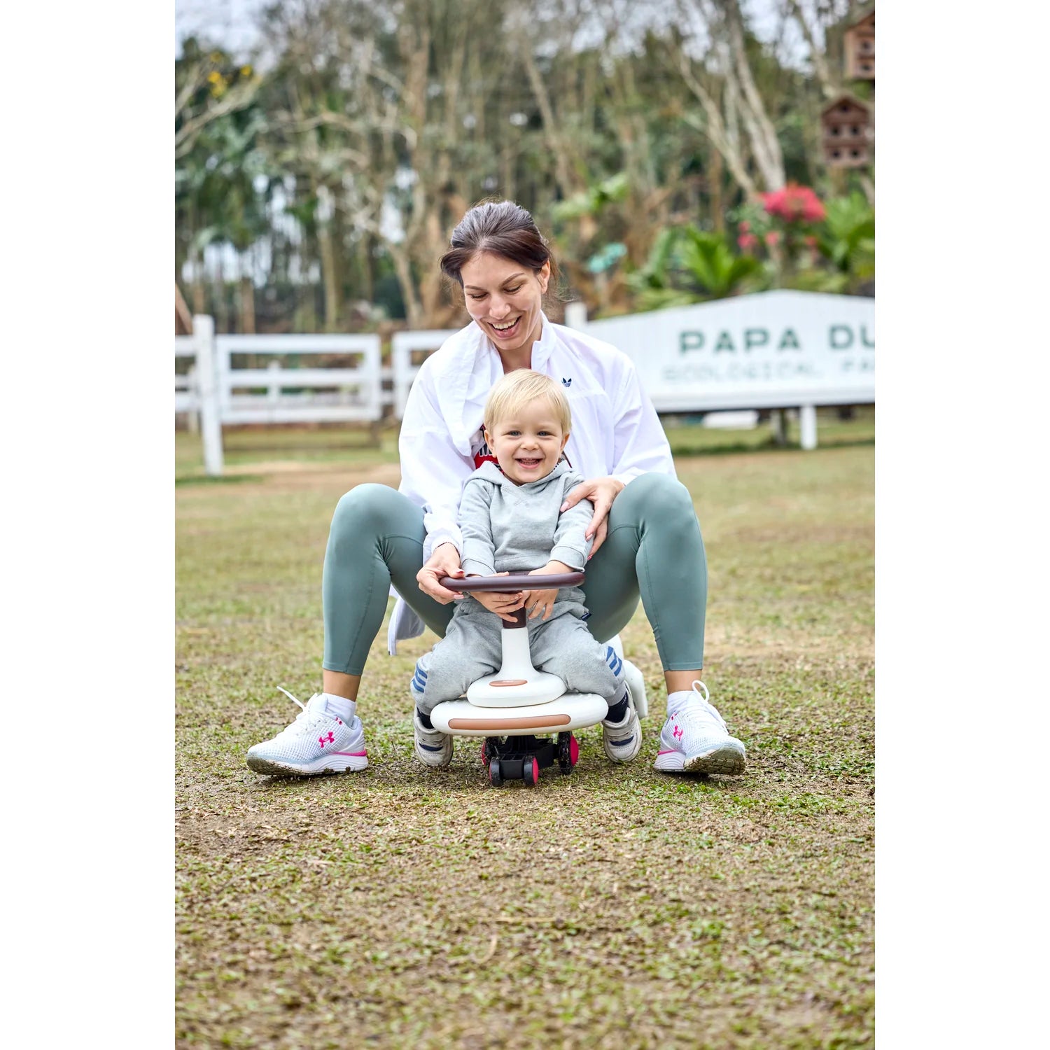 Woman and child playing with a scooter in an outdoor setting