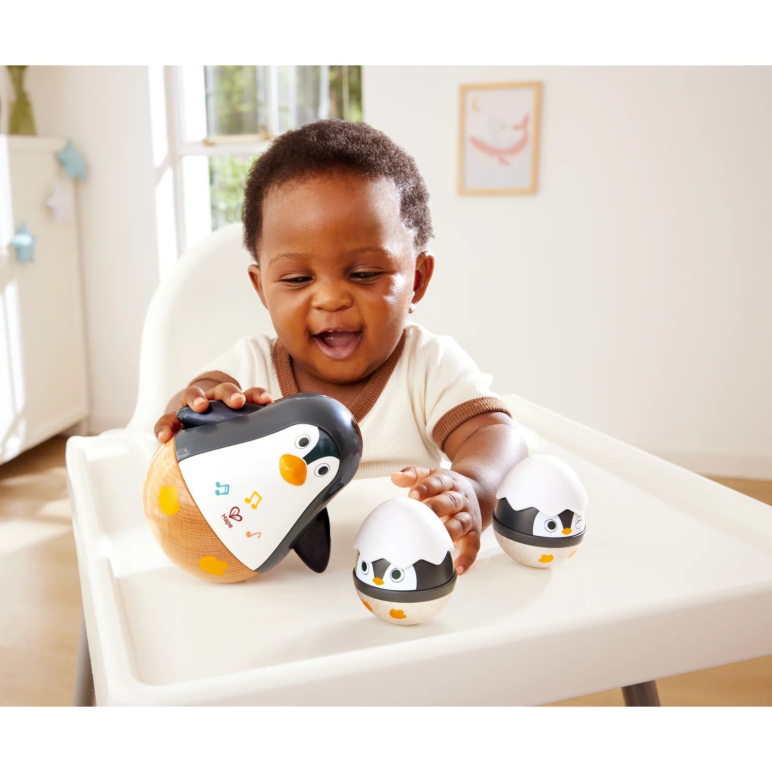 Baby playing with penguin toys in a high chair