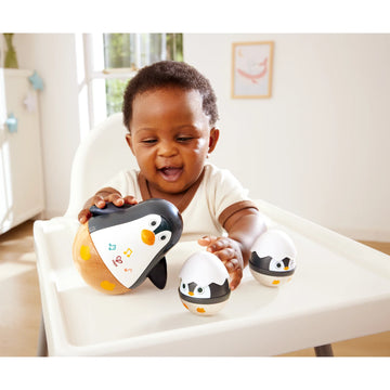 Baby playing with penguin toys in a high chair
