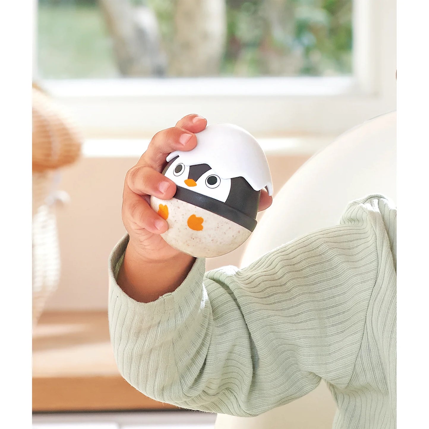 Child holding a penguin-shaped toy in a cozy indoor setting