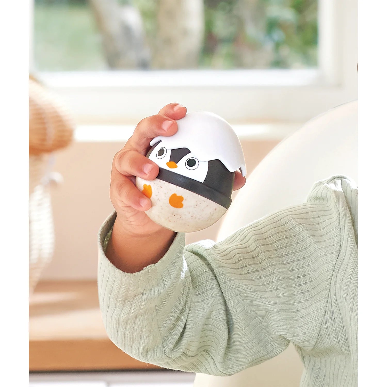 Child holding a penguin-shaped toy in a cozy indoor setting